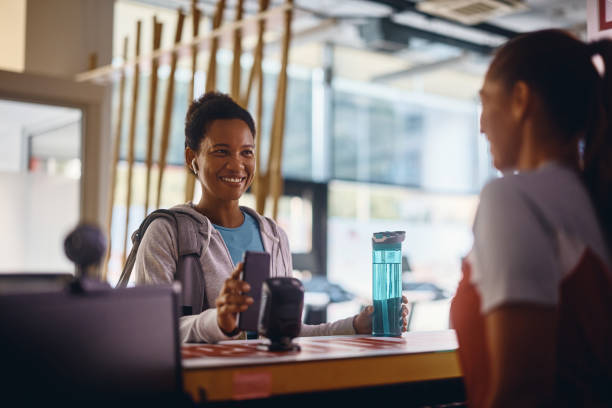 Member checking in at a gym front desk with a retail display, illustrating retail revenue in fitness clubs and point-of-sale operations for wellness centers.